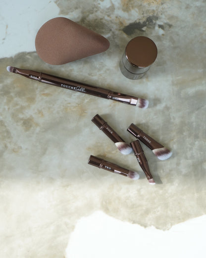 Touché Salli Six In One Brush System makeupbørster med 6 aftagelige børstehoveder i vegansk, syntetisk hår. og en brun makeup svamp.